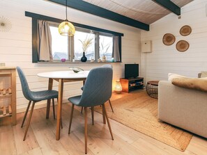 Un salon confortable avec un canapé, une table à manger et des chaises, un téléviseur et une fenêtre avec des rideaux.