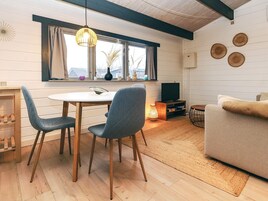A cozy living room with a sofa, a dining table with chairs, a TV, and a window with curtains.