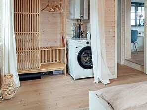 A laundry room with a washing machine, wooden shelves, and a hanging rack. - 4 Person Holiday Home in Karrebaeksminde (Karrebæksminde)
