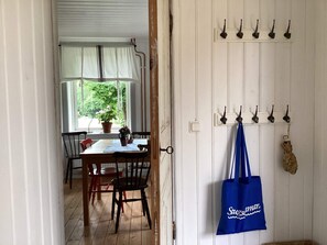 An interior view of a room with a dining table, chairs, a potted plant, and a wall-mounted coat rack with a blue bag. - 7 Person Holiday Home in Motala (Motala)