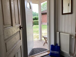 A doorway leading to a covered outdoor area with a bench and a blue bag on the floor. - 7 Person Holiday Home in Motala (Motala)