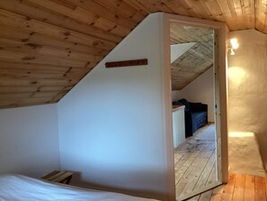 A room with a sloped ceiling, a visible doorway leading to another room, and a light fixture on the wall. - 7 Person Holiday Home in Motala (Motala)