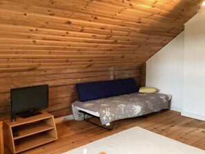 A small, sloped ceiling room with a bed, a television on a wooden stand, and a white rug. - 7 Person Holiday Home in Motala (Motala)