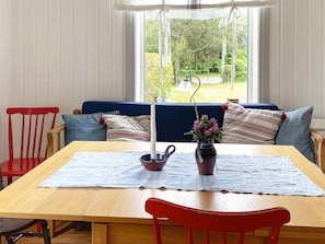 A dining area with a wooden table, a blue cushioned bench, and a red chair. - 7 Person Holiday Home in Motala (Motala)