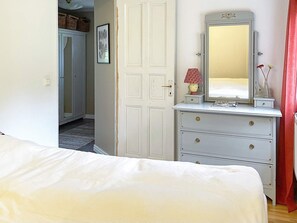 A bedroom with a bed, a dresser, a mirror, and a door leading to another room. - 7 Person Holiday Home in Motala (Motala)