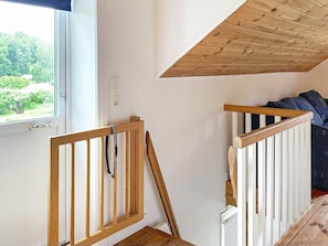 A room with a wooden staircase, a window with a view of greenery, and a white wall. - 7 Person Holiday Home in Motala (Motala)