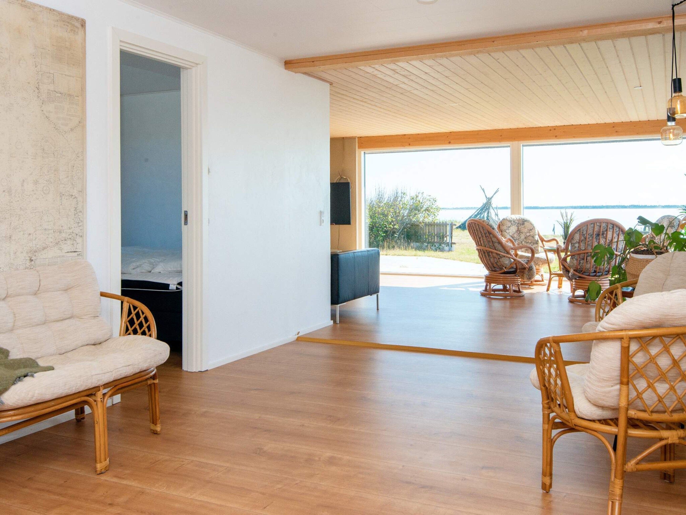 A spacious living area with wicker furniture, a flat-screen TV, and a view of the outdoors.