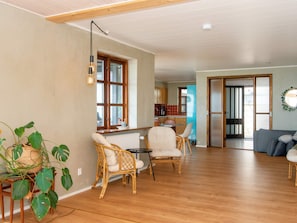 A spacious living area with wooden flooring, a dining table with chairs, and a kitchen in the background. - 8 Person Holiday Home in Ulfborg (Ulfborg)