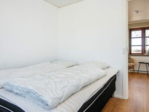 A single bed with white bedding in a room with white walls and wooden flooring. - 8 Person Holiday Home in Ulfborg (Ulfborg)