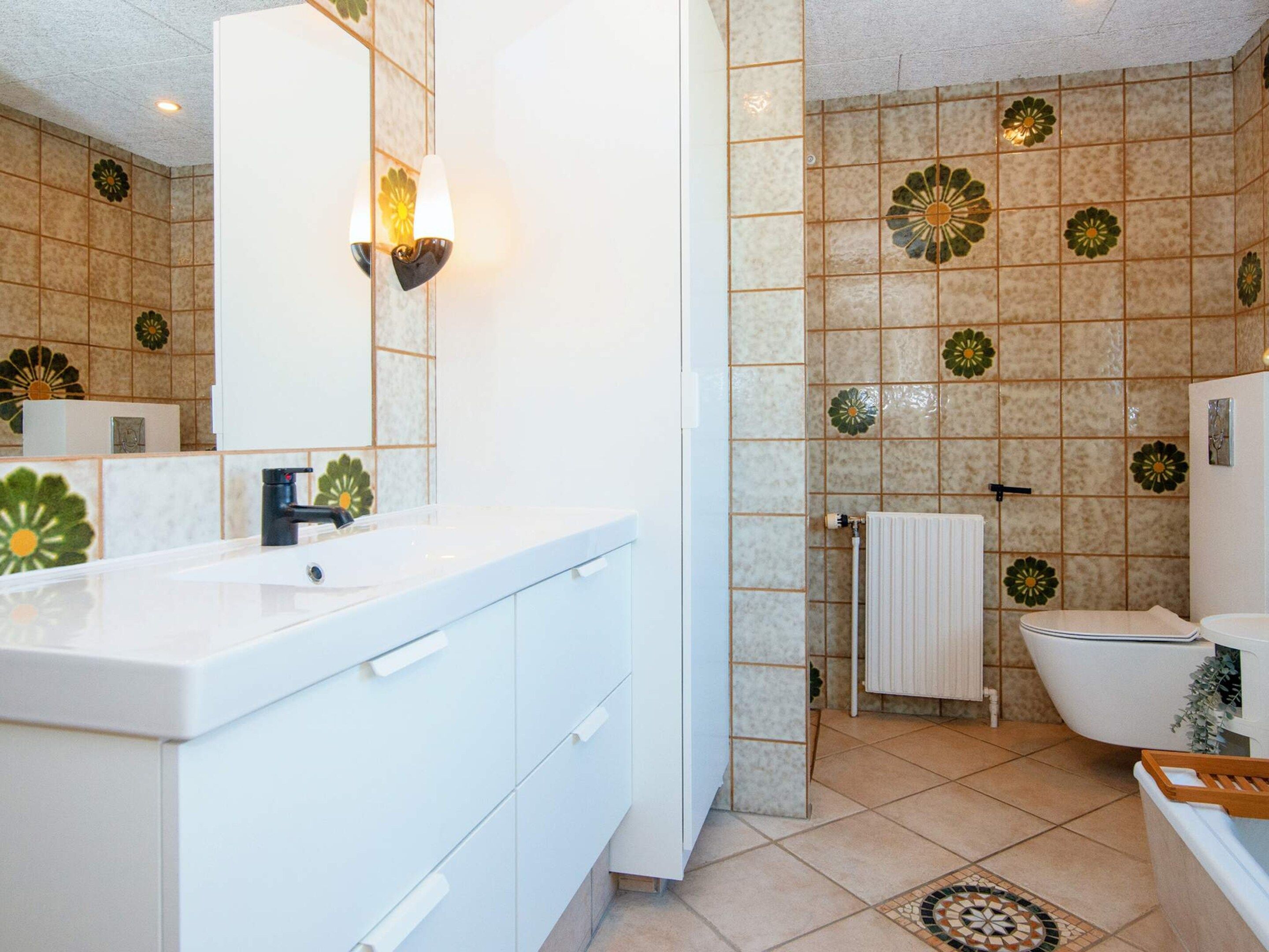 A bathroom with a white sink, a mirror, a towel rack, and a toilet.