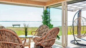 Ein Zimmer mit Korbmöbeln, einem Glastisch und Blick auf einen See.