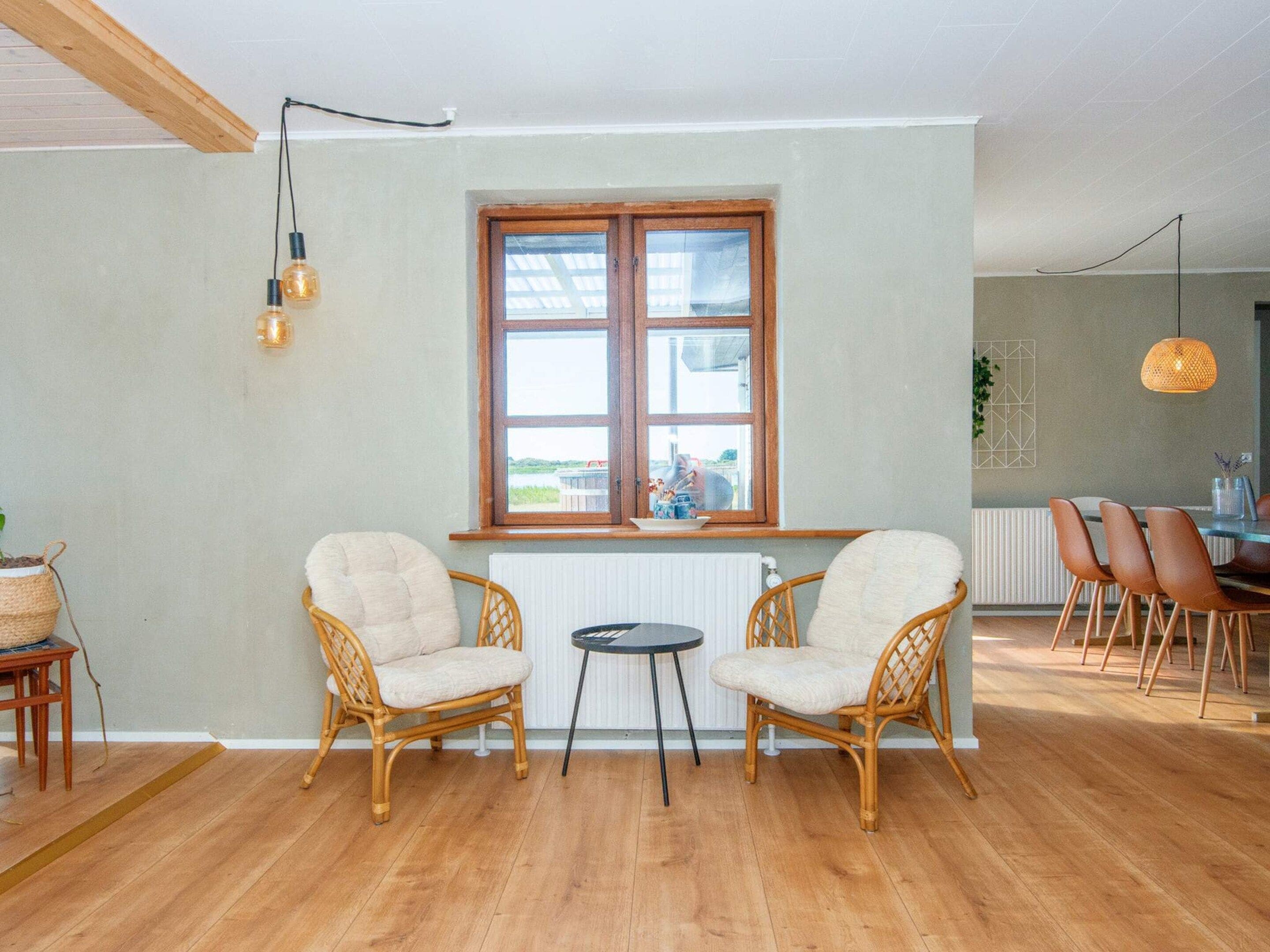 Una habitación acogedora con dos sillas de mimbre, una mesita redonda y un ventanal con vistas.