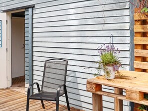Une terrasse en bois avec une chaise en métal et une table en bois sur laquelle est posée une plante en pot.