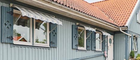 A building with a red-tiled roof, blue siding, and a front porch with steps leading to the entrance.