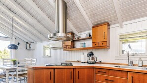 A modern kitchen with wooden cabinets, a stainless steel range hood, and a large island. - 6 Person Holiday Home in Vaeggerlose (Vaeggerlose)