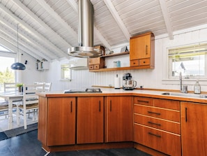 A modern kitchen with wooden cabinets, a stainless steel range hood, and a large island. - 6 Person Holiday Home in Vaeggerlose (Vaeggerlose)