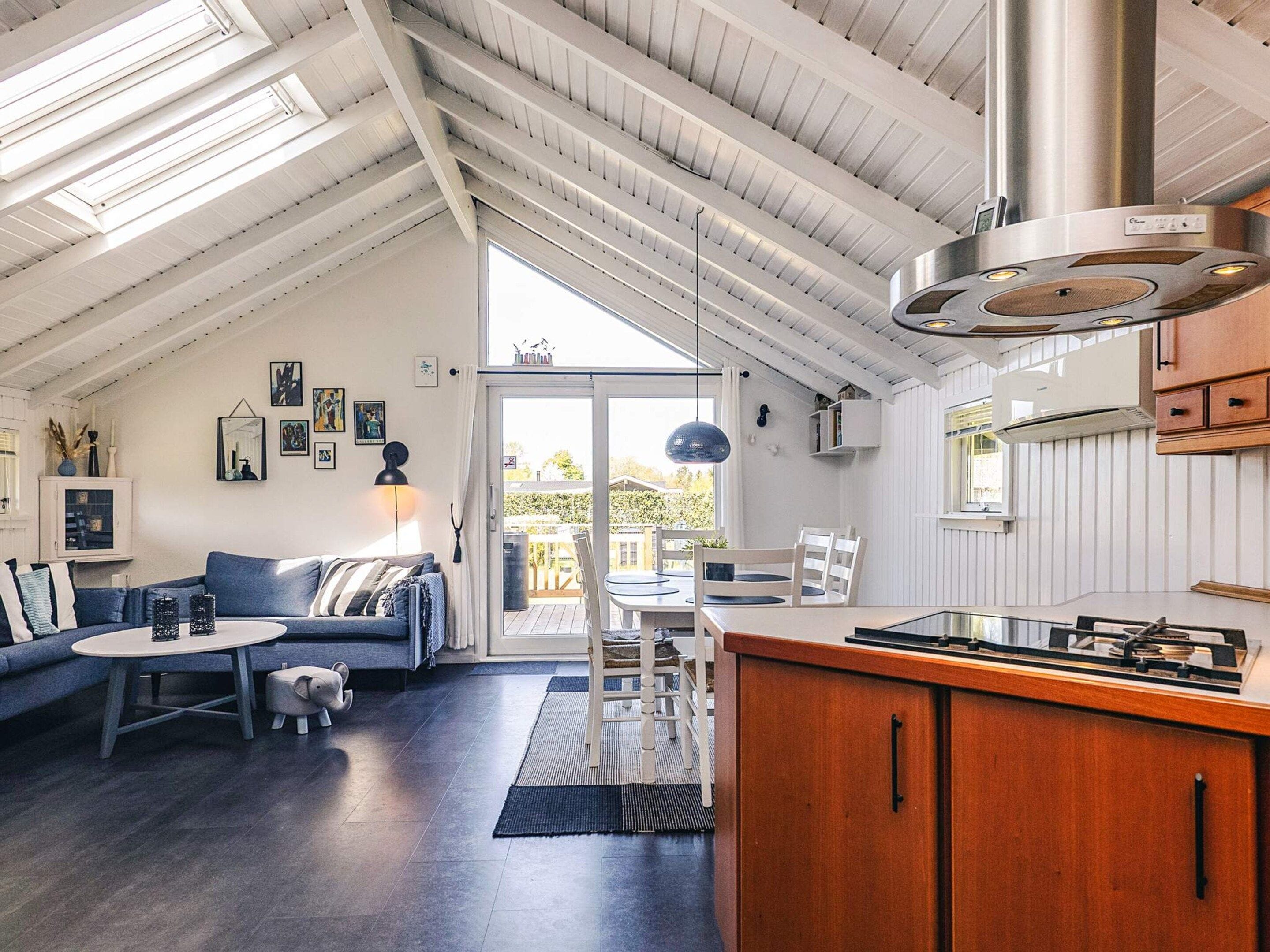 Um espaço de estar moderno estilo loft, com cozinha, área de jantar e uma grande porta de vidro deslizante para o exterior.