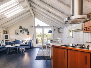 Un loft spacieux avec un plafond haut, un coin repas, une cuisine équipée d’une cuisinière et une grande porte-fenêtre coulissante donnant sur une terrasse extérieure.