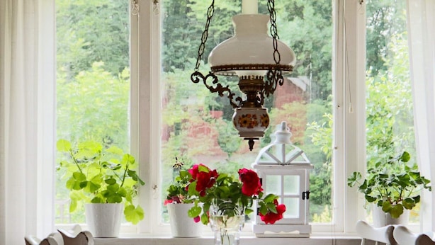 A dining table with white chairs, a vase with flowers, and a hanging lamp. - 6 Person Holiday Home in Laholm (Laholm)