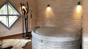 Una habitación con sauna de piedra, paredes de madera y un amplio ventanal.