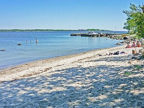 A sandy beach with calm water, a dock, and a few people. - 4 Person Holiday Home in Drottningskar (Drottningskär)