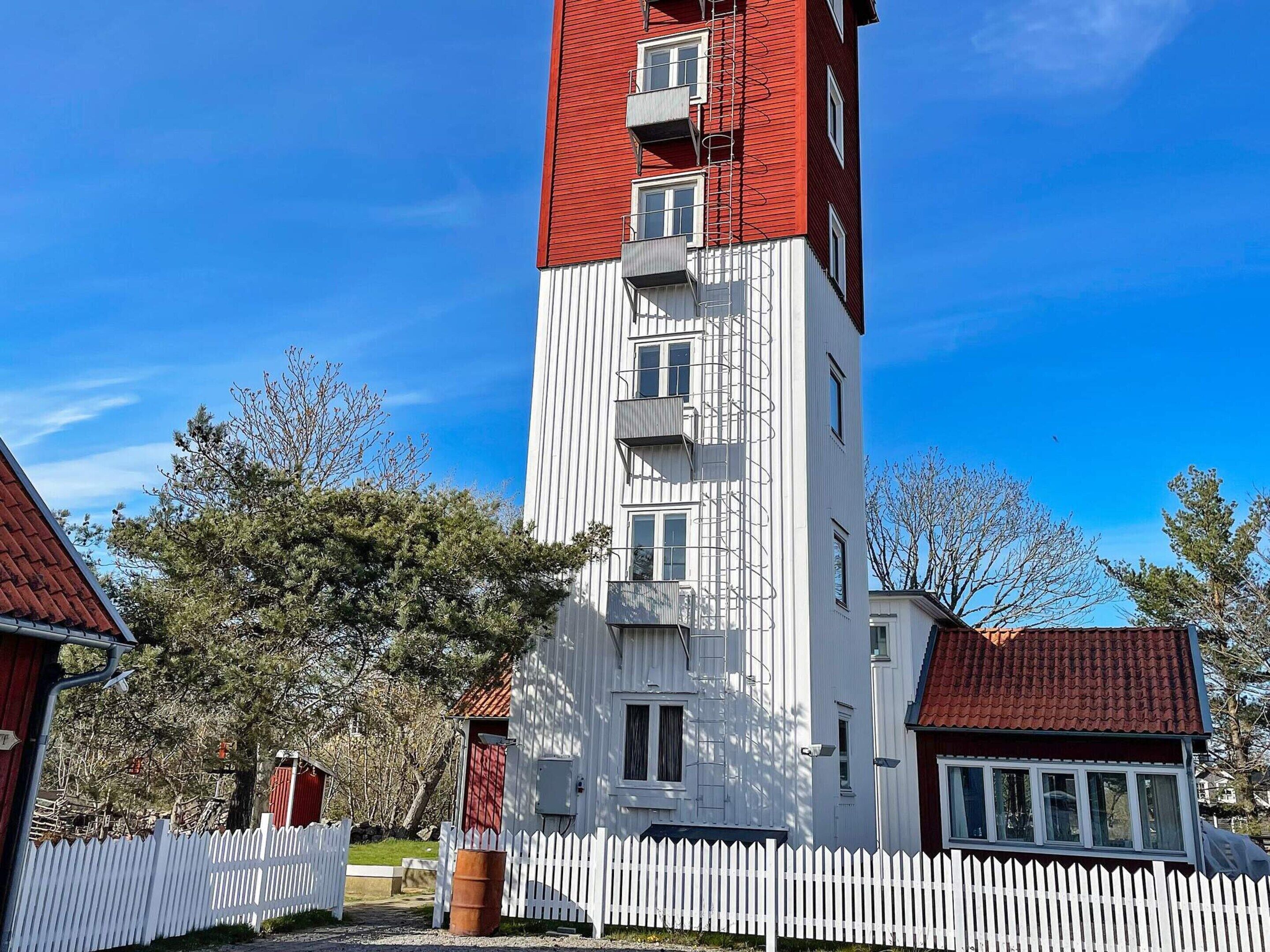 Ein mehrstöckiges Gebäude mit roter und weißer Fassade, einem weißen Zaun und Bäumen im Hintergrund.