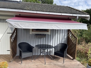A covered patio with two chairs and a table, a white exterior wall, and a metal roof. - 4 Person Holiday Home in Drottningskar (Drottningskär)