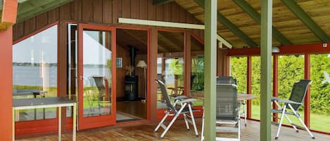 A wooden deck with outdoor seating, a covered area with a grill, and a view of a lake.