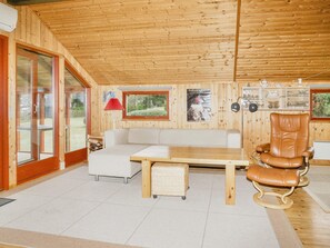 A wooden interior with a sofa, a chair, a small table, and a wicker basket. - 5 Person Holiday Home in Jaegerspris (Jægerspris)