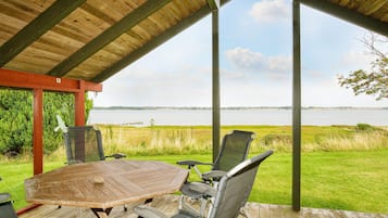An outdoor seating area with a wooden table and chairs, overlooking a body of water.