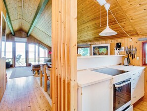 A wooden interior with a kitchen area featuring a stove, sink, and hanging knives. - 5 Person Holiday Home in Jaegerspris (Jægerspris)