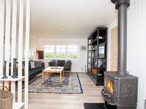 A cozy living room with a fireplace, a sofa, a coffee table, and a bookshelf. - 8 Person Holiday Home in Lokken (Lokken)