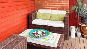 A wicker outdoor seating area with a table set for two, a potted plant, and a brick wall in the background. - 4 Star Holiday Home in Dio (Diö)