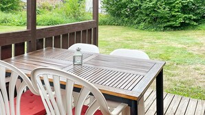 A wooden deck with a table and chairs, surrounded by greenery. - 4 Star Holiday Home in Dio (Diö)