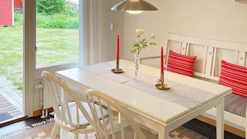 Un comedor con una mesa, sillas, una lámpara colgante y vistas al exterior.
