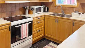 A kitchen with wooden cabinets, a microwave, a stove, and a sink. - 4 Star Holiday Home in Dio (Diö)