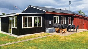 A black and red building with a covered patio area and a grill. - 6 Person Holiday Home in Hadsund (Hadsund)