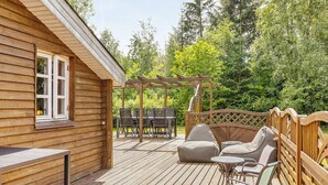 Puinen terassi, jossa on pergola, ulkokalusteita ja pöytä.