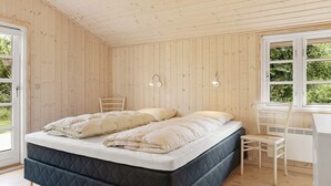 Makuuhuoneessa on sänky, tuoli, työpöytä ja ikkuna, josta on näkymä vehreään maisemaan.