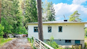 A white building with a metal roof, surrounded by trees and a dirt path. - 6 Person Holiday Home in Henan (Henån)