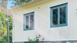 A two-story building with a light-colored exterior and blue trim around the windows. - 6 Person Holiday Home in Henan (Henån)