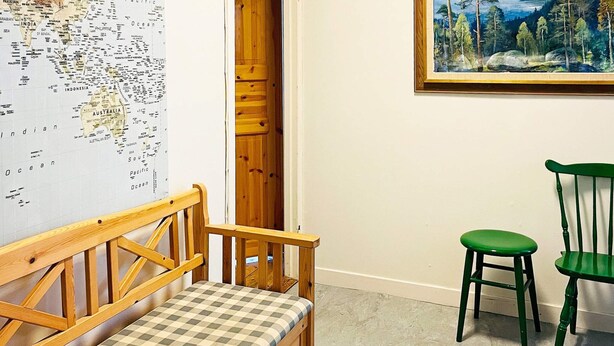 A room with a wooden bench, a green chair, a map on the wall, and a painting. - 6 Person Holiday Home in Henan (Henån)