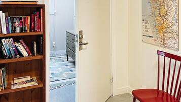 A room with a bookshelf, a red chair, a door leading to another room, and a map on the wall.