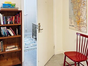 A room with a bookshelf, a red chair, a door leading to another room, and a map on the wall. - 6 Person Holiday Home in Henan (Henån)