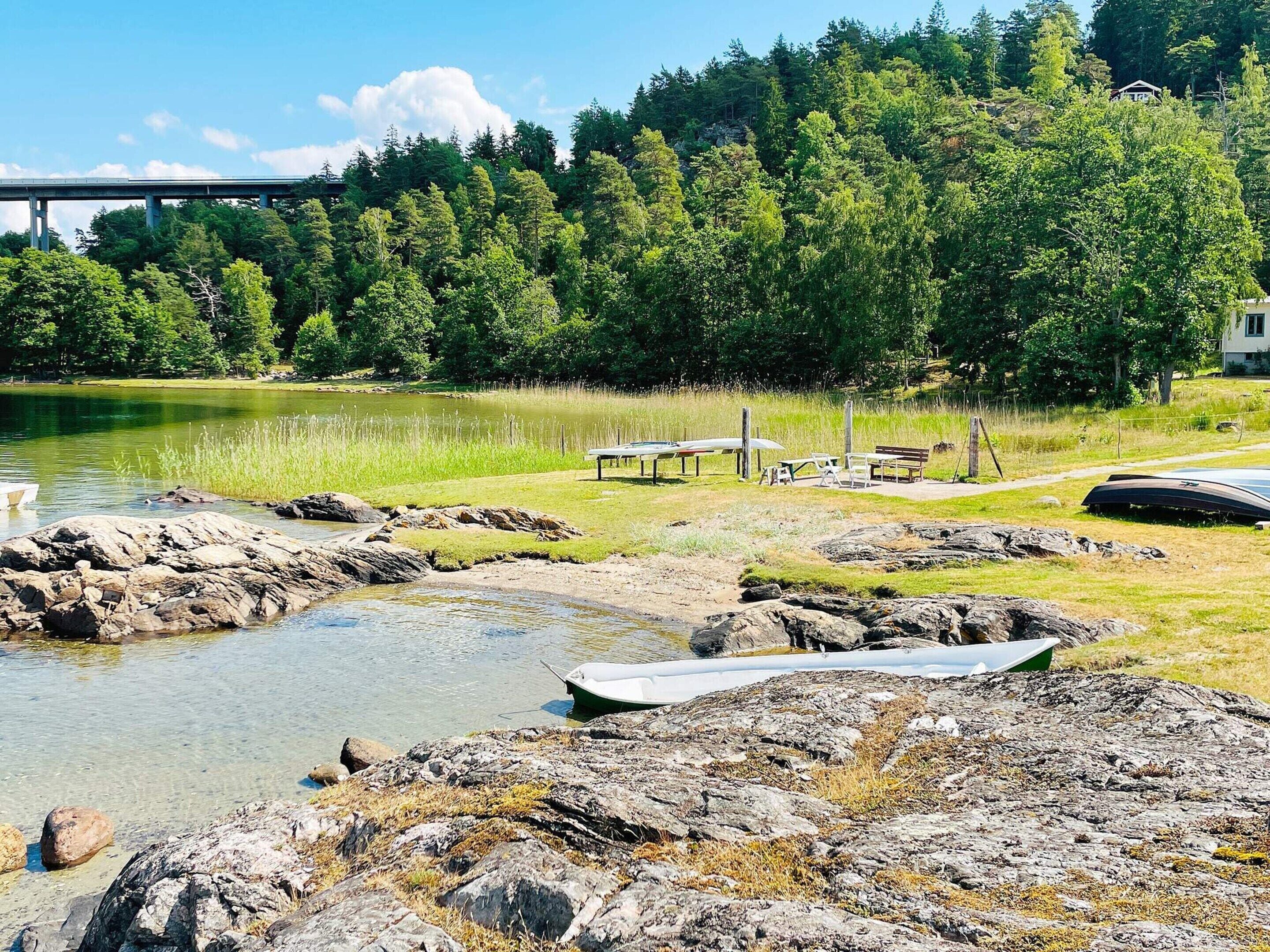A lakeside view with boats, a picnic area, and a bridge in the background.