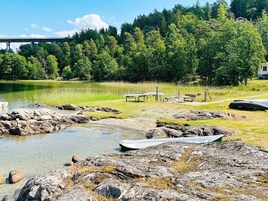 Vista de un lago con botes, una zona de picnic y un puente al fondo.
