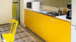 A kitchen with yellow cabinets, a white countertop, a sink, a microwave, and a coffee maker. - 6 Person Holiday Home in Henan (Henån)