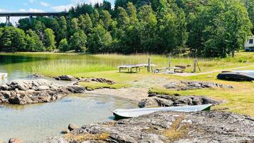 A lakeside view with a bridge, picnic tables, and boats.