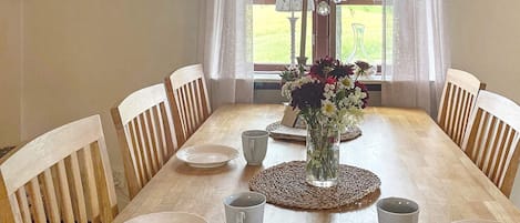 A dining table with chairs, a vase with flowers, and a chandelier.
