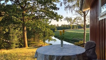 Una mesa de piedra con una silla frente a un edificio, con vistas a un río y follaje.